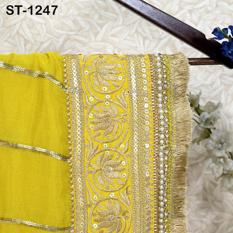 a yellow fabric with intricate gold embroidery and a fringe design, hanging on a wooden hanger.