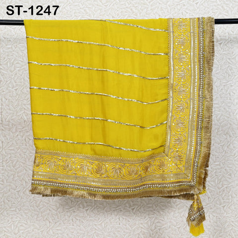 a yellow and gold embroidered fabric hanging on a black rod.