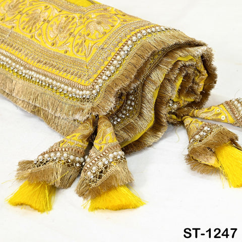 A decorative yellow and gold fabric with intricate embroidery and tassels, displayed on a white background.