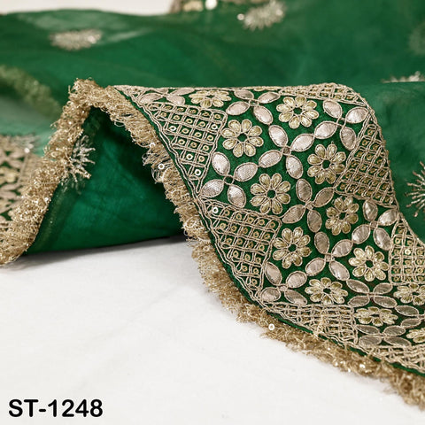 a close-up view of a green fabric with intricate gold embroidery and fringed edges.