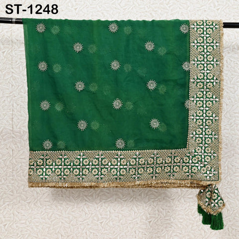 a green and gold embroidered fabric with a floral pattern, hanging on a black rod.