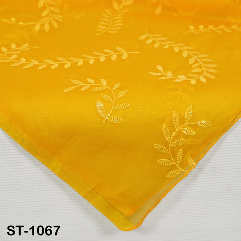 a close-up view of a yellow fabric with white leaf and flower embroidery patterns.
