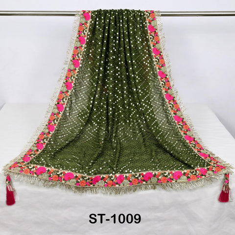 a green and pink floral embroidered shawl with a tassel at the bottom, hanging on a metal rod.