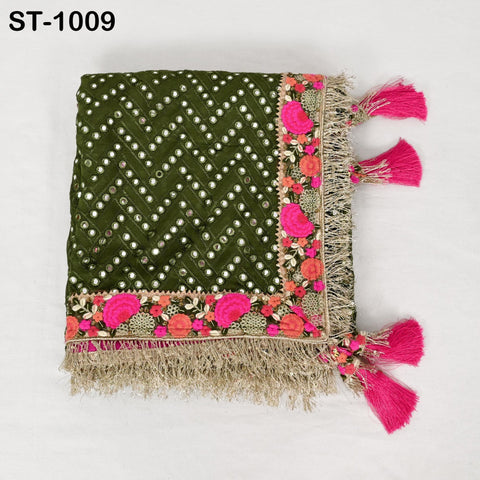 a decorative textile with a green and pink floral pattern, tassels, and fringe trim.