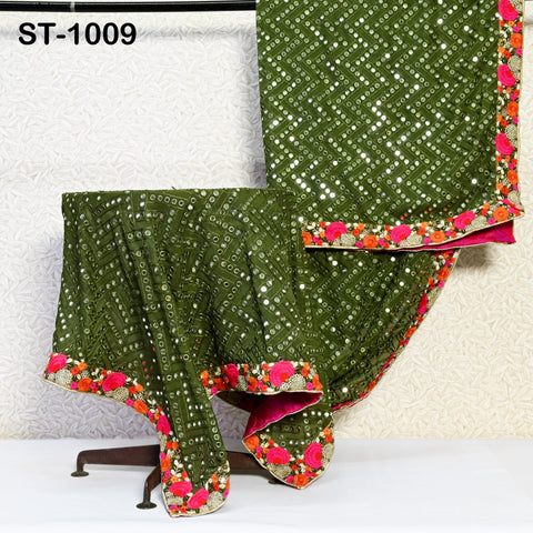 a green and pink patterned fabric with a floral design, displayed on a stand against a white wall.