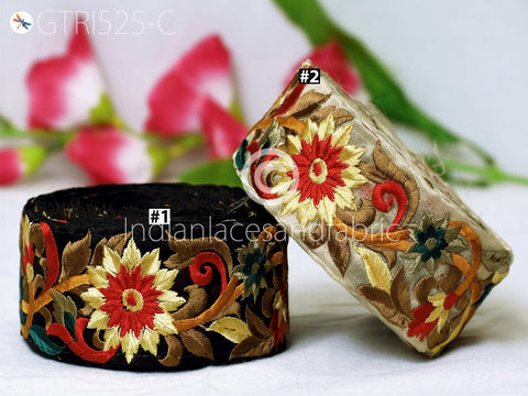 two decorative fabric pieces with intricate floral embroidery, including red, yellow, and green flowers, as well as leaves and other natural elements. The background is blurred, drawing focus to the colorful and detailed fabric pieces.
