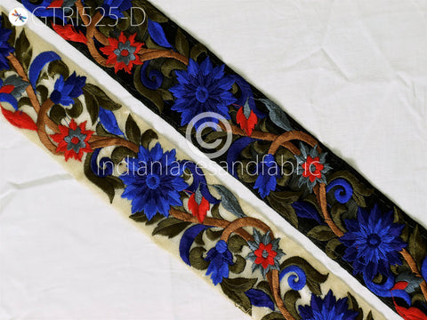 a decorative fabric with a floral pattern in shades of blue, red, and green. The fabric appears to be a piece of embroidered material, with intricate designs and patterns created using various colors and techniques.