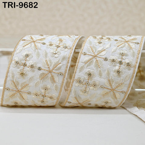 two pieces of white fabric with gold embroidered designs, including flowers and leaves, arranged on a white surface.