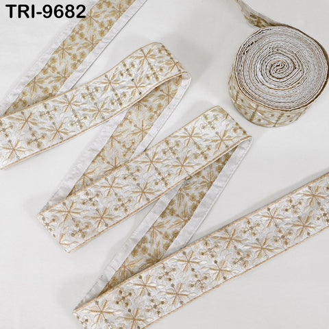 a collection of decorative fabric pieces, including a long ribbon with a floral pattern and a smaller piece of fabric with a similar design. The items appear to be made of a shiny, metallic material and are arranged on a white background.