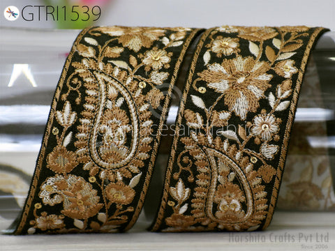 a close-up view of a decorative fabric with intricate floral and paisley patterns in gold and black. The fabric appears to be a decorative textile, possibly used for embellishing clothing or accessories.