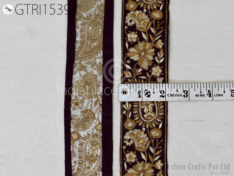 two decorative fabric pieces with intricate patterns and designs, including floral and paisley motifs, placed next to a ruler for size comparison.