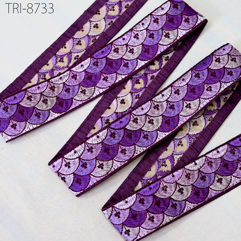 a collection of purple and white fabric pieces with a repeating pattern of scales or waves, arranged in a row.