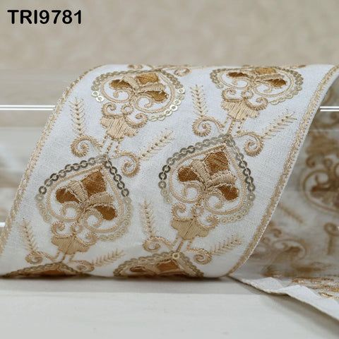 a close-up view of a decorative fabric with intricate gold embroidery patterns.