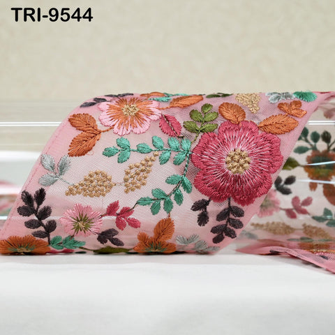 a pink fabric with a floral pattern, including various flowers and leaves in different colors such as pink, orange, green, and brown.