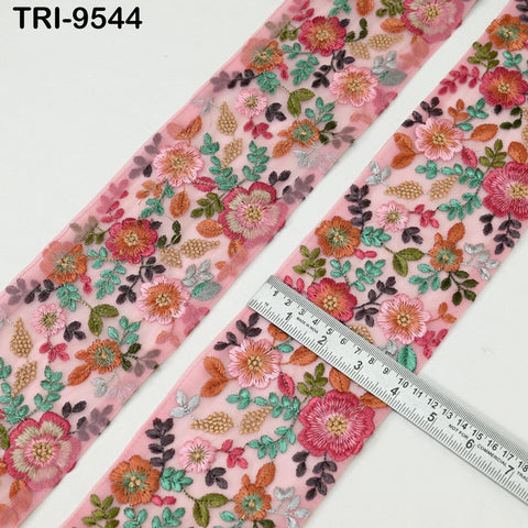 a close-up view of a fabric with a floral pattern, featuring a variety of colorful flowers and leaves. A ruler is placed on the fabric, likely for size reference or measurement purposes.