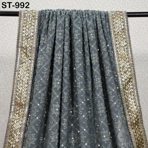 a grey and gold embroidered fabric with a metallic border, hanging on a black rod.