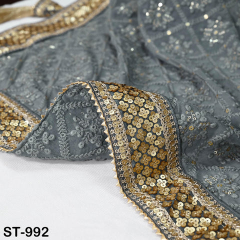 a close-up view of a gray fabric with gold and silver sequin embellishments, including a decorative border.