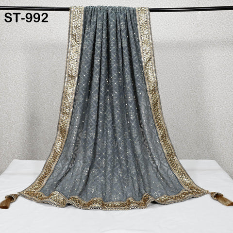 a gray and gold embroidered shawl or scarf hanging on a black rod.