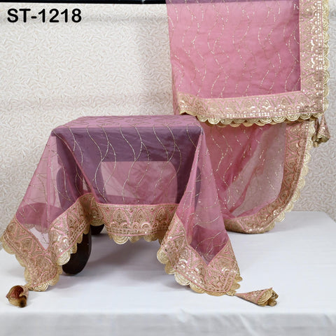 a pink and gold saree with intricate embroidery and a matching pink tablecloth.