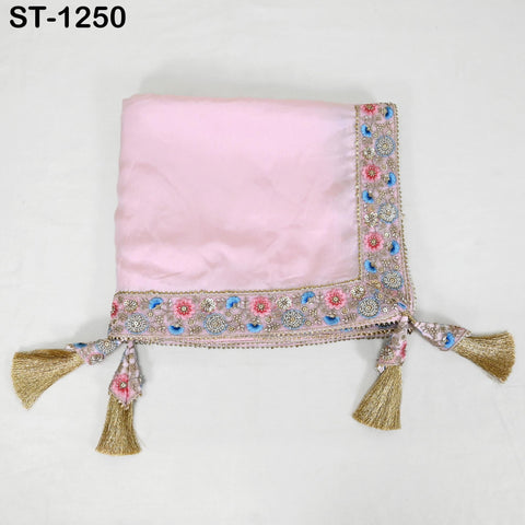 A pink fabric with a decorative border and tassels, placed on a white background.