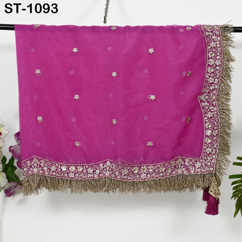 a pink fabric with a decorative border, hanging on a hanger.