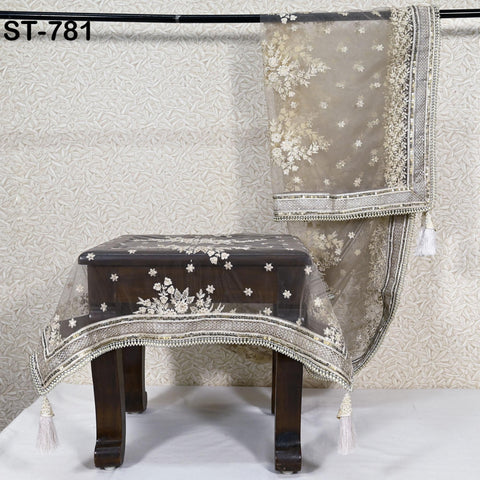 a wooden table with a decorative tablecloth, and a small stool or chair with a similar tablecloth draped over it.