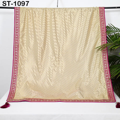 a beige and pink patterned fabric hanging on a rack, with a plant visible in the background.