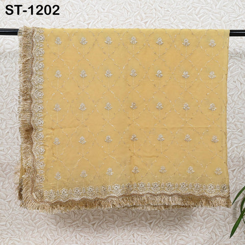 a yellow fabric with a gold and white floral pattern, hanging on a wall. The fabric appears to be a decorative textile, possibly a shawl or a blanket.