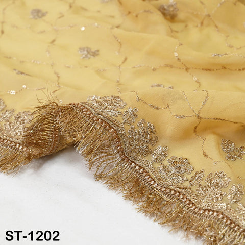 a close-up view of a yellow fabric with intricate gold embroidery and fringe details.