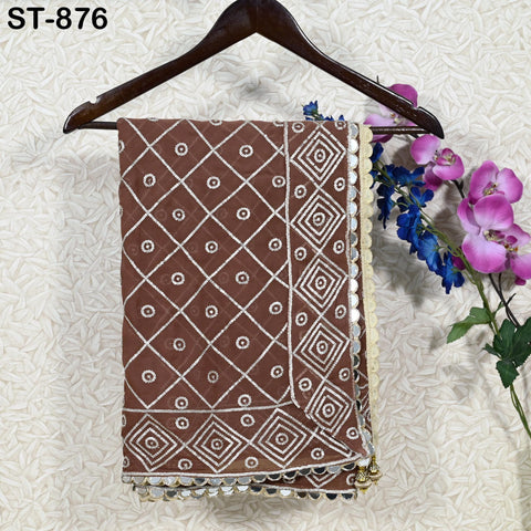 a brown and white patterned fabric hanging on a wooden hanger, with a bouquet of purple flowers placed next to it on a wall.