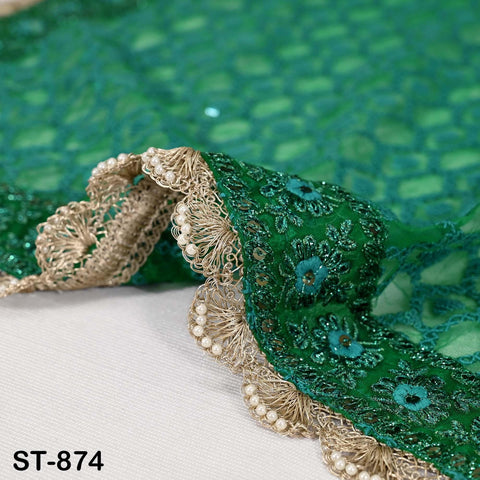 a close-up view of a green and gold embroidered fabric with a delicate lace trim.