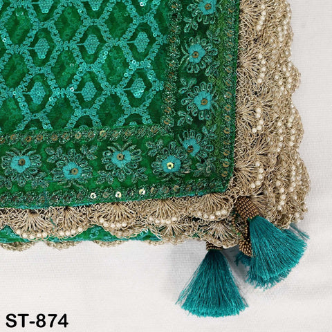 a close-up view of a decorative textile with a green and gold pattern. The textile features intricate embroidery and tassels in shades of green and gold, creating a visually appealing and ornate design.