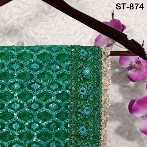 a green and gold sequined saree hanging on a wooden hanger, with purple orchids in the background.