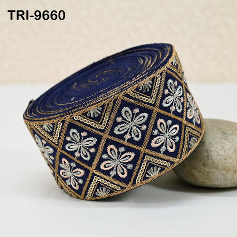 A decorative blue and gold fabric with a floral pattern, placed on a white surface next to a rock.