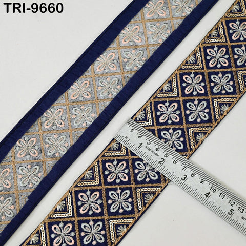 a close-up view of a decorative fabric with a repeating pattern of blue and gold floral designs. A ruler is placed on the fabric, indicating its size or dimensions.