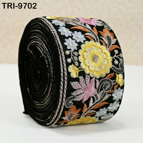 A roll of black fabric with a colorful floral embroidered design on it.