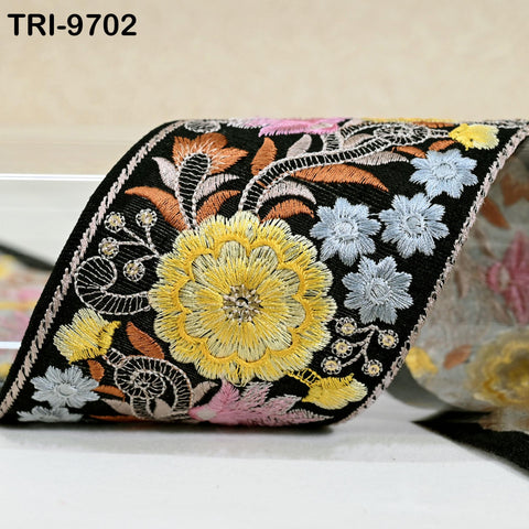 a close-up view of a decorative fabric with a floral pattern, including yellow and pink flowers, against a black background.