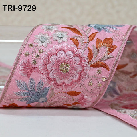 A close-up image of a pink fabric with a floral pattern, featuring a large pink flower and smaller flowers in shades of white and blue.