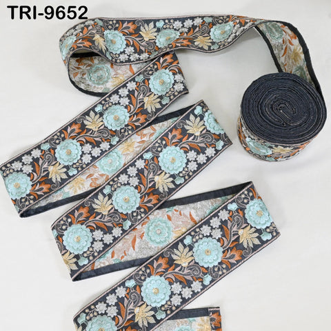 a roll of decorative fabric with a floral pattern in shades of blue, green, and orange. The fabric appears to be a decorative trim or border, possibly used for sewing or other textile applications.