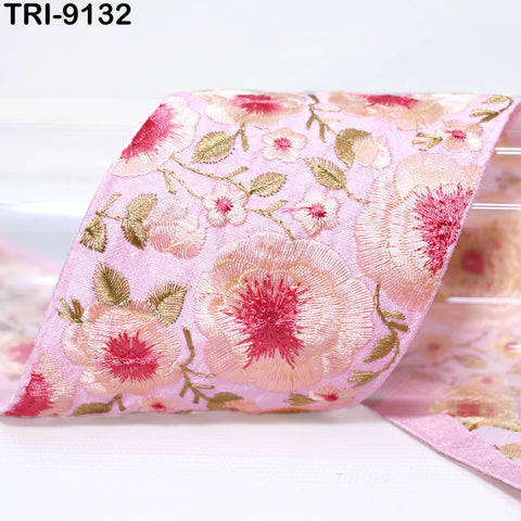 a close-up view of a pink fabric with a floral pattern, featuring red and green flowers and leaves.