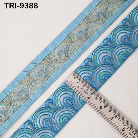a close-up view of a blue and green embroidered fabric with a ruler placed on top of it, indicating the size of the fabric.