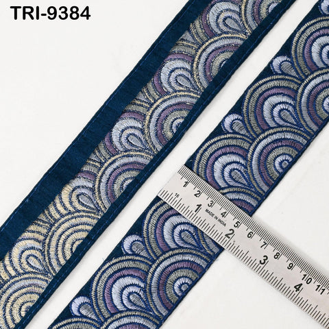 a close-up view of a decorative blue fabric with a repeating pattern of waves or swirls in shades of blue, purple, and gold. A ruler is placed next to the fabric, indicating the size of the pattern.