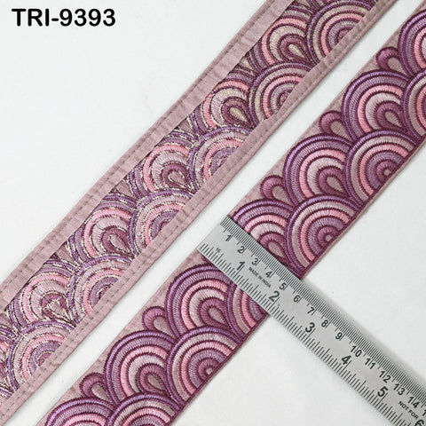 a close-up view of a decorative ribbon with a repeating pattern of pink and purple waves. A ruler is placed on the ribbon, indicating its size.