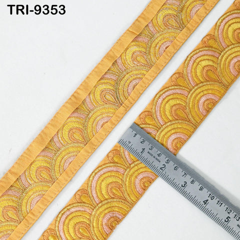 a close-up view of a decorative fabric with a repeating pattern of yellow and pink circles, and a ruler is placed next to it to measure the length of the fabric.