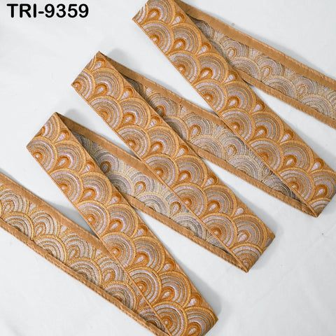 a collection of decorative fabric pieces with a repeating pattern of circles in shades of gold and brown. The fabric appears to be made of silk or a similar material, and the pattern is intricate and visually appealing.