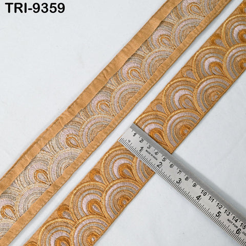 a close-up view of a decorative fabric with a repeating pattern of gold and white waves. A ruler is placed next to the fabric, indicating the size of the pattern.