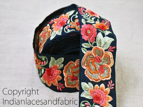 A close-up image of a decorative fabric with a floral pattern in shades of blue, orange, and green.