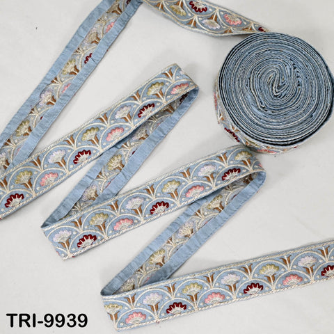 a collection of blue and white embroidered fabric pieces, including a large roll of the same fabric and several smaller pieces.
