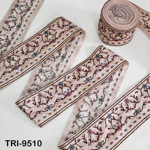 a collection of decorative fabric pieces with floral patterns, including a spool of pink and brown embroidered fabric.