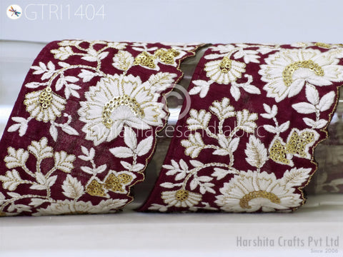 a close-up view of a decorative fabric with a floral pattern in shades of red and white. The fabric appears to be made of a material with gold embroidery, adding a touch of elegance and sophistication to the design. The image does not contain any text, and the focus is on the intricate details and patterns of the fabric.